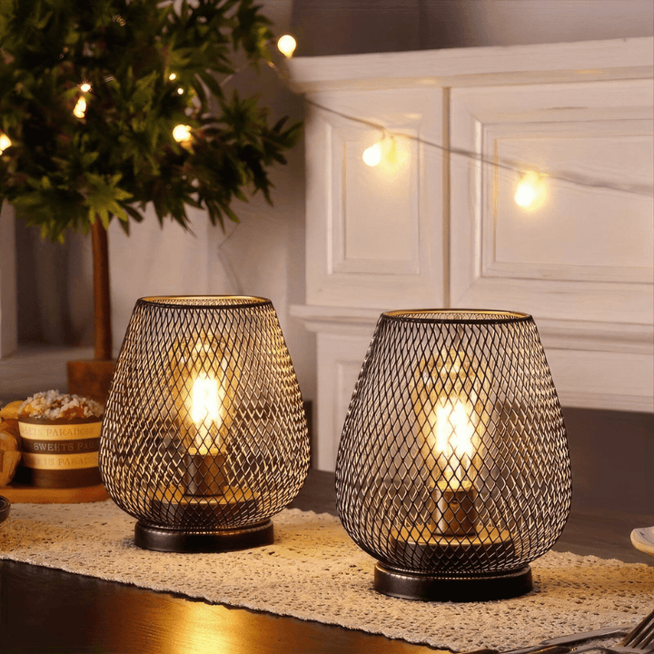 Two modern wireless metal LED lanterns glowing on a dining table decorated with a lace runner.