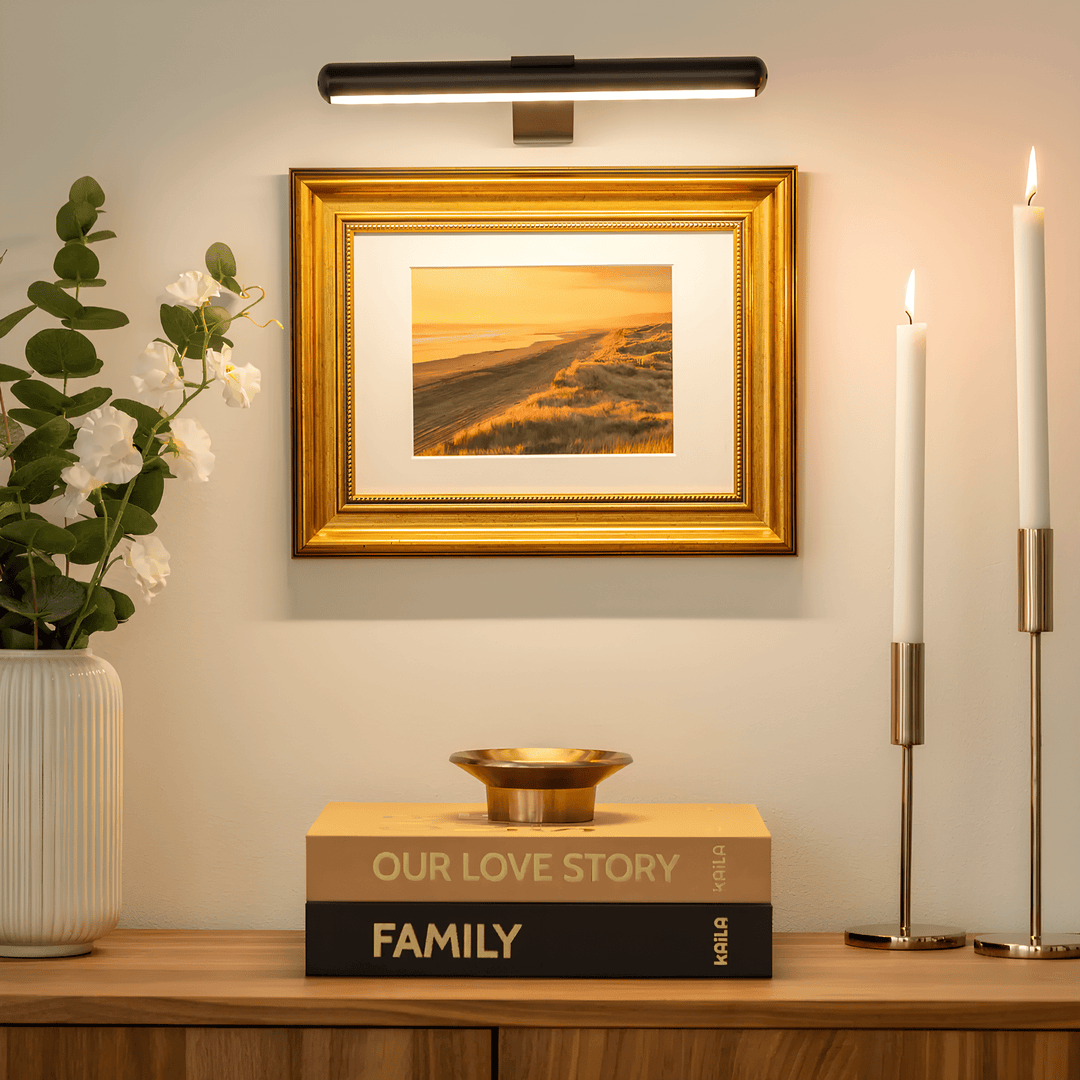 Black wireless LED picture light mounted above a framed landscape painting in a cozy living room