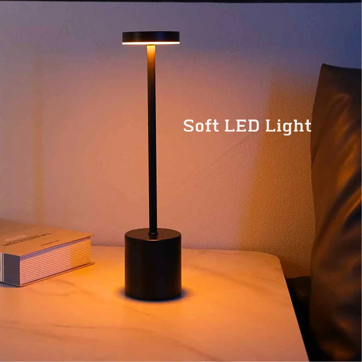 Black wireless metal LED table lamp casting a warm glow on a nightstand