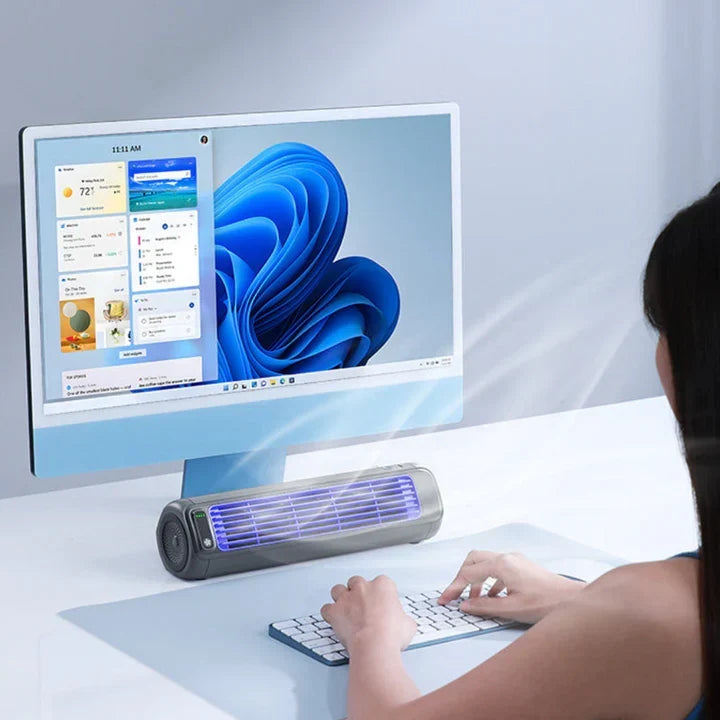 The portable air conditioner placed neatly on a modern office desk next to a computer monitor.
