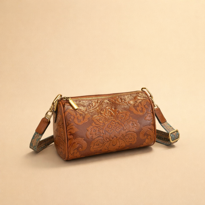 Brown vintage embossed floral pattern cylinder crossbody bag on a neutral background