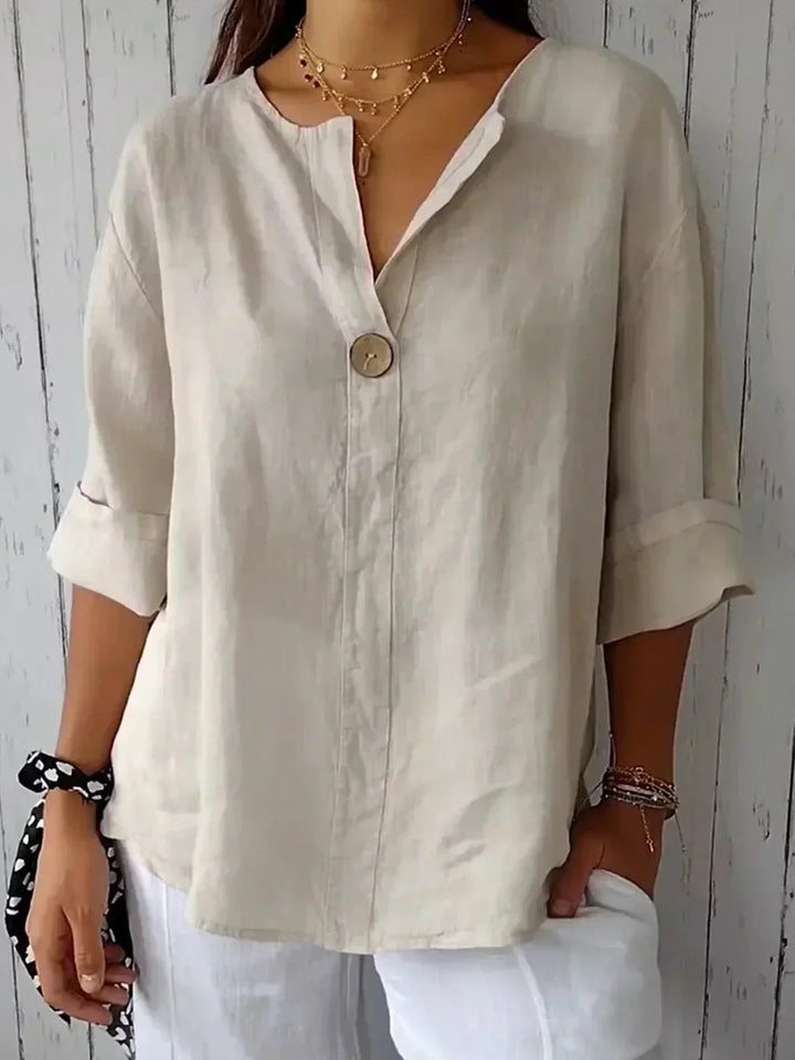 Woman wearing a beige V-neck button-down blouse with rolled-up sleeves