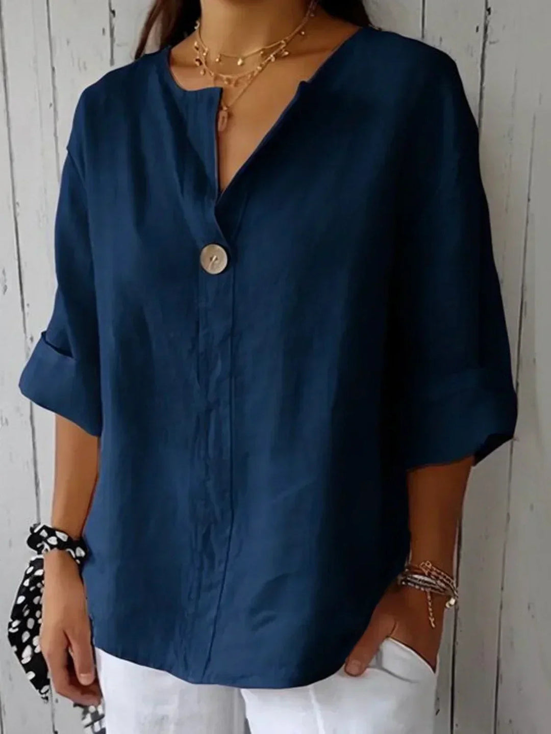 Woman wearing a navy blue V-neck button-down blouse with 3/4 sleeves