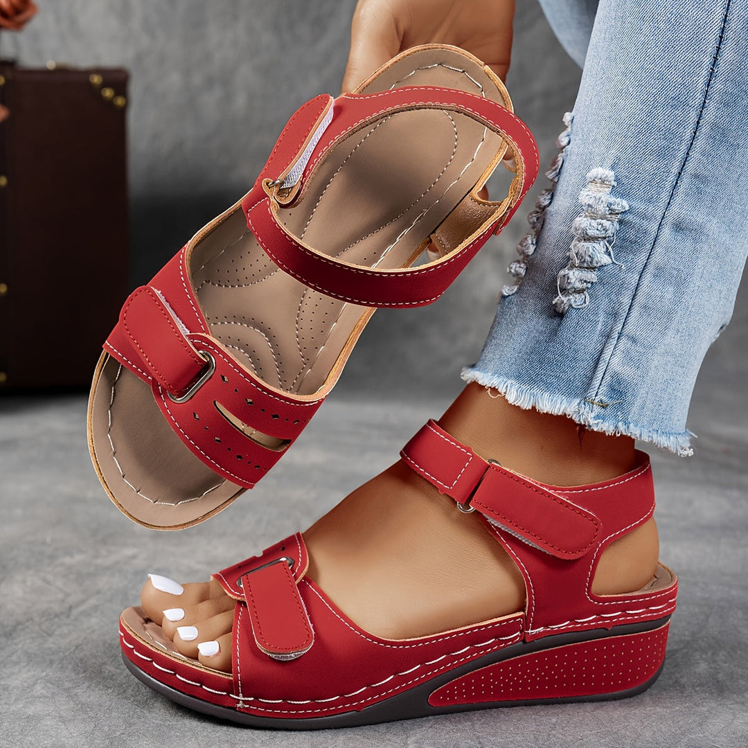 Woman holding red orthopedic comfort sandal with adjustable straps