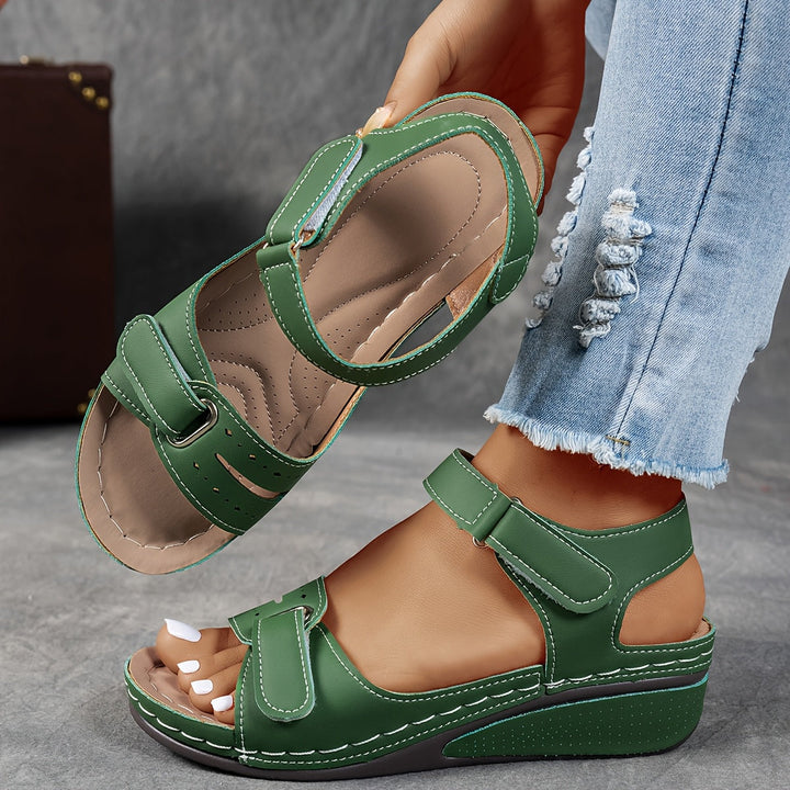 Woman holding green orthopedic comfort sandal with adjustable straps