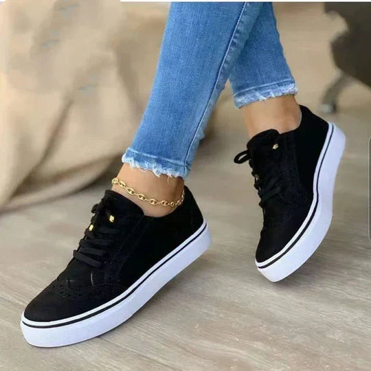 Women wearing black lace-up sneakers paired with blue jeans