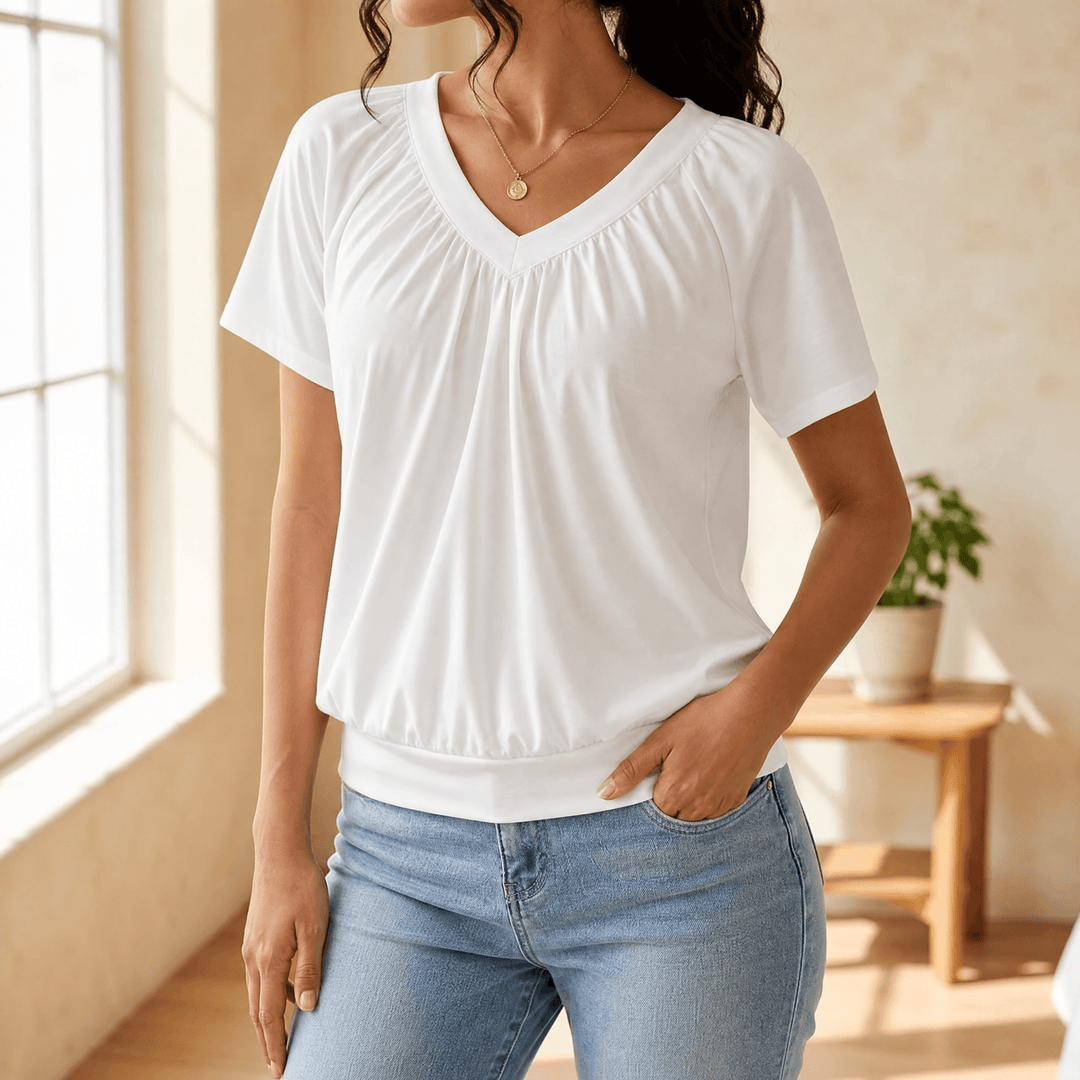 Woman wearing a white pleated V-neck blouson top with jeans