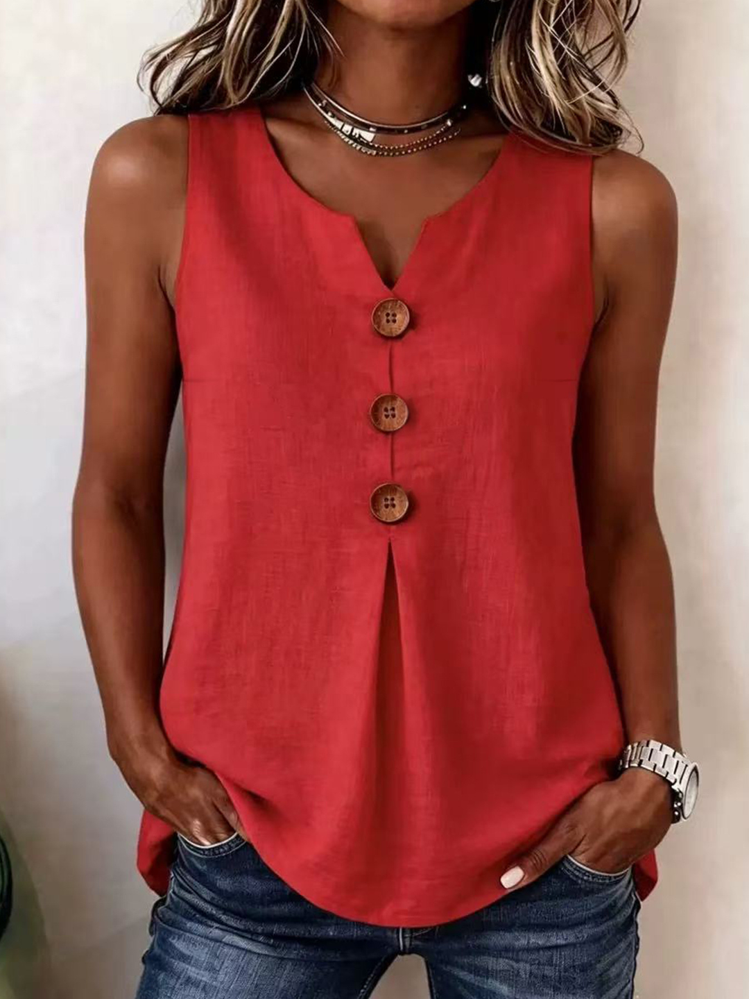 Woman wearing a red sleeveless V-neck blouse with front buttons and pleats