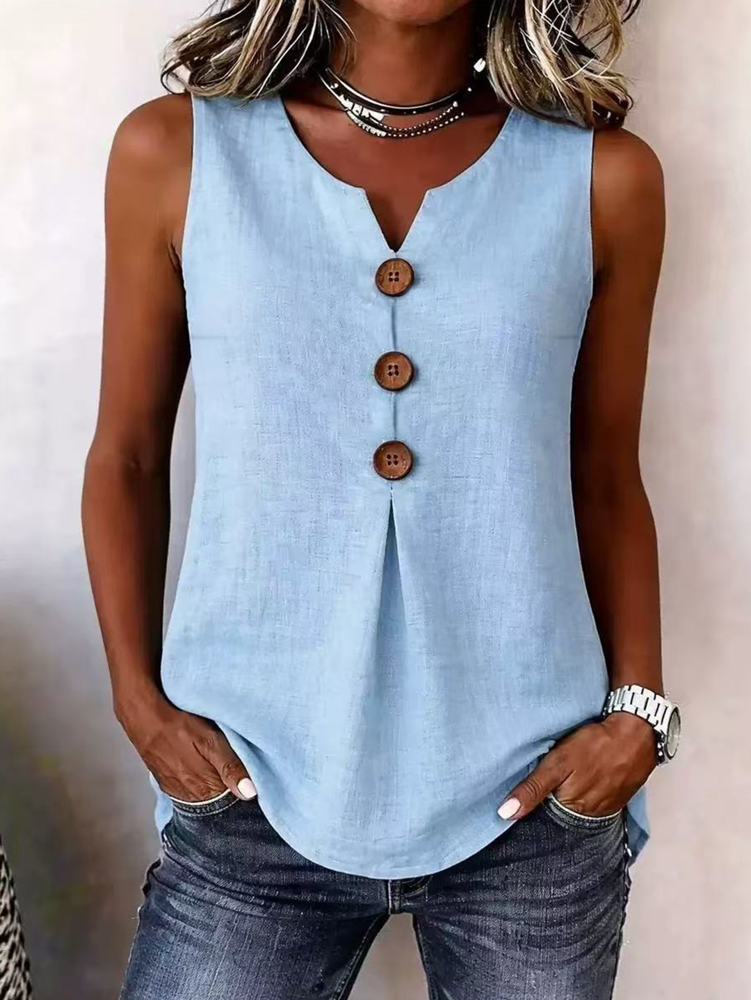 Close-up view of the V-neckline and pleated detail on the sleeveless blouse