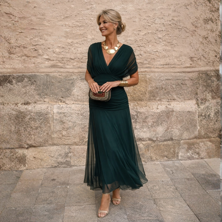 Woman wearing a dark green V-neck flutter-sleeve midi dress outdoors