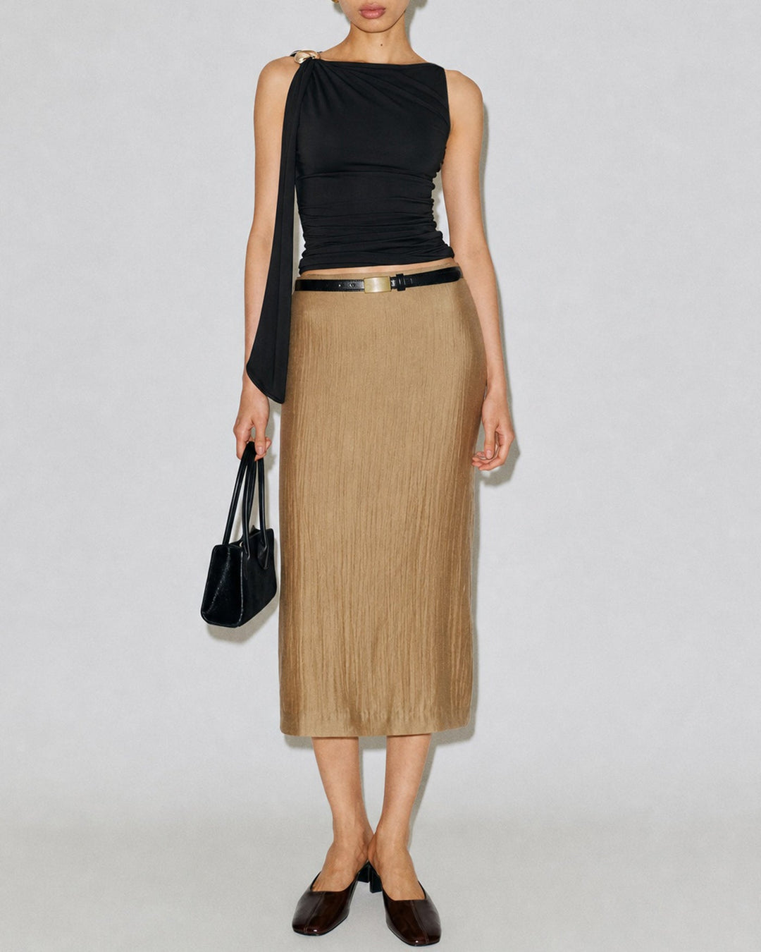 Full outfit view of woman wearing black boat-neck tank top with camel midi skirt