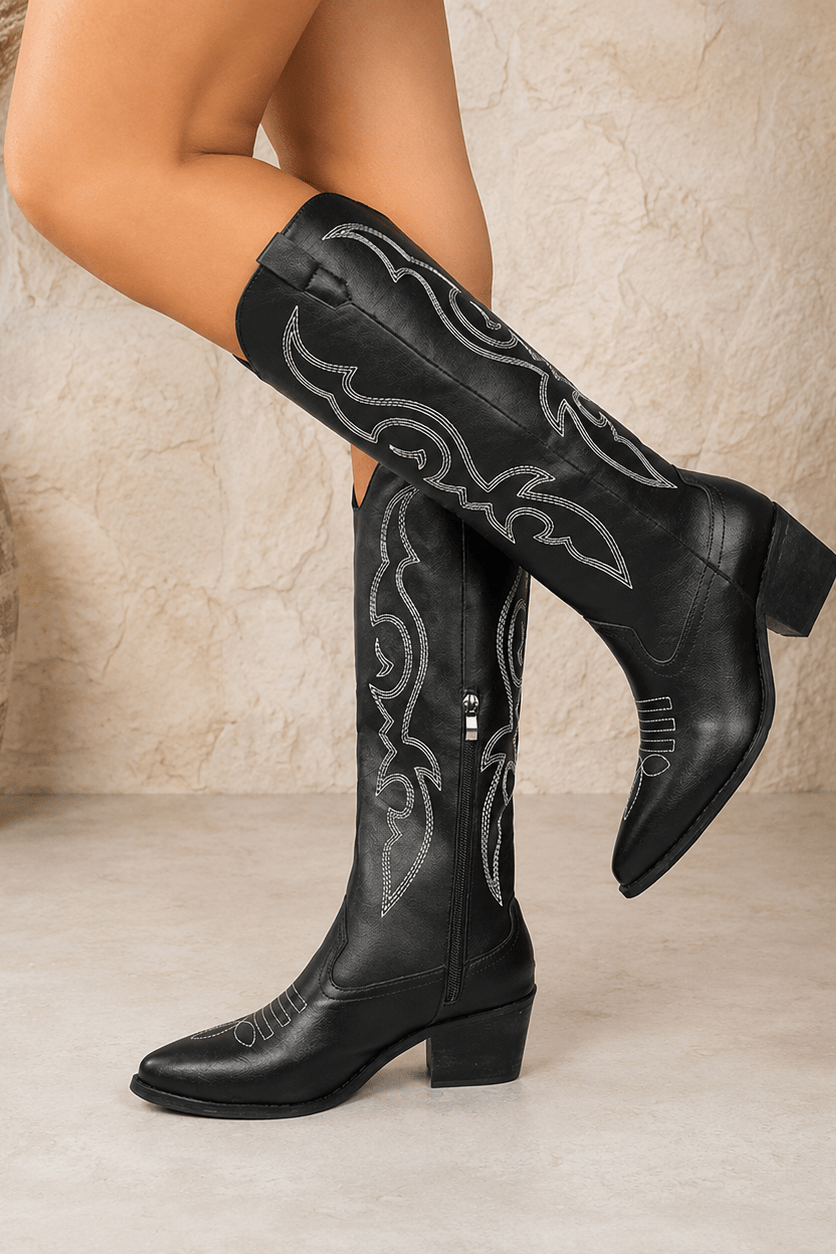 Black women's western cowboy boots with contrast stitching and pointed toe worn by model