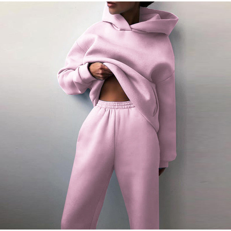 Woman showcasing light pink high waist jogger tracksuit set against a plain wall