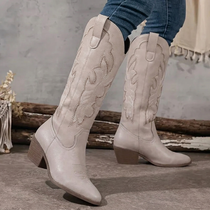 Beige women's knee-high cowboy boots featuring pointed toe and western stitching