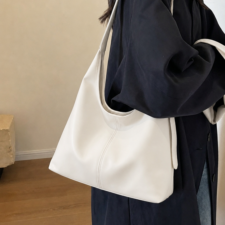 Model wearing a white slouchy shoulder tote bag and dark coat