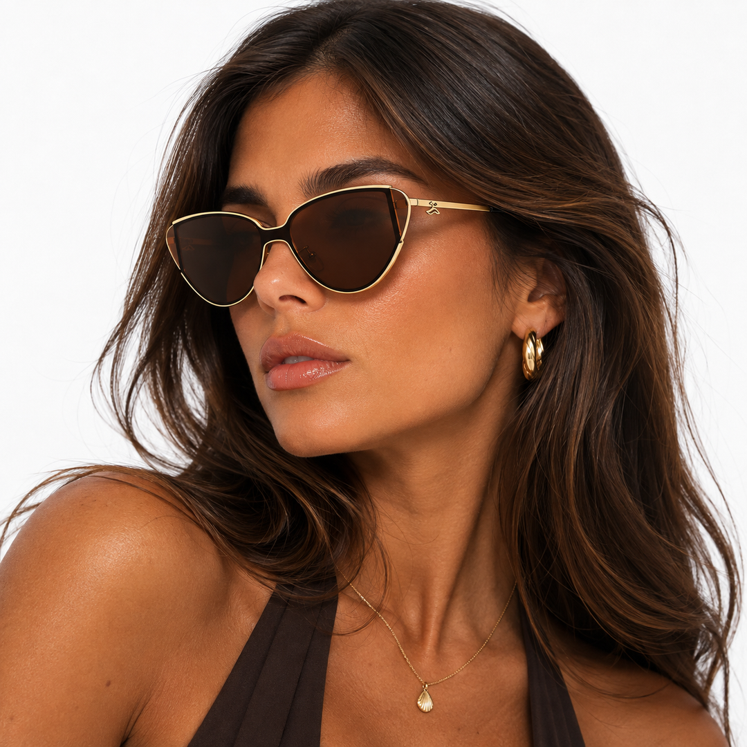 Model wearing stylish gold triangular cat-eye sunglasses with warm lenses