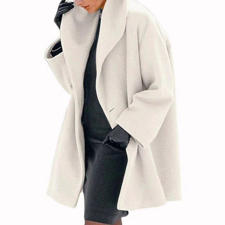 Woman wearing a creme colored elegant winter jacket with a wide lapel collar