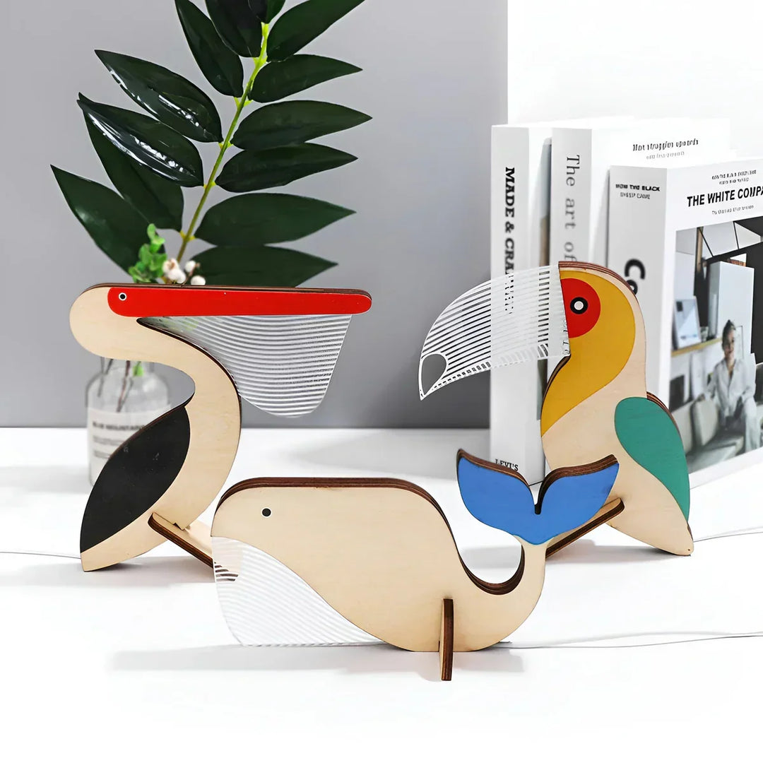 Wooden animal table lamps featuring pelican, toucan, and whale designs displayed on a shelf.