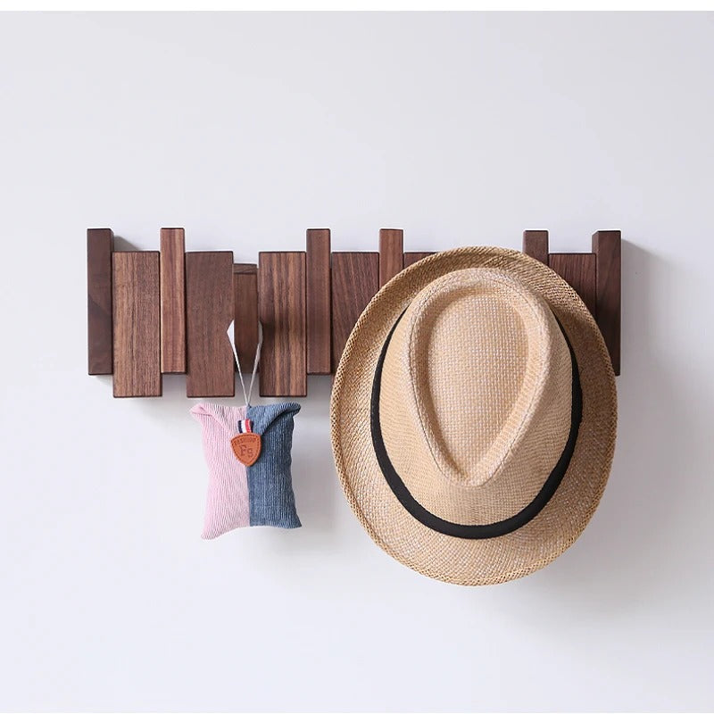 Wooden piano coat rack styled with a straw hat and small pouch on a wall