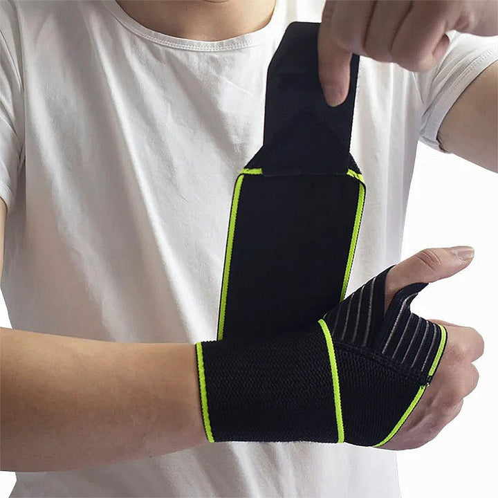 Person wearing an adjustable black wrist and thumb support brace with green trim