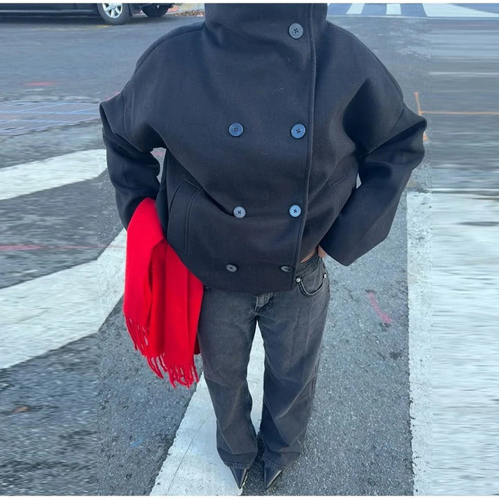 Full view of black high neck short jacket paired with gray jeans